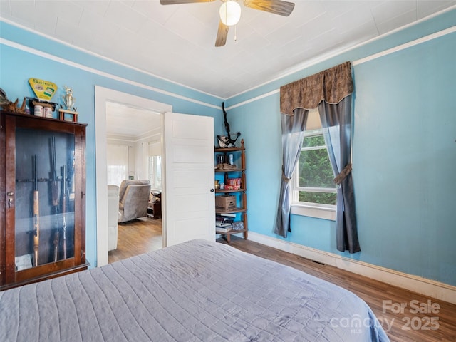 bedroom with crown molding, hardwood / wood-style floors, and ceiling fan