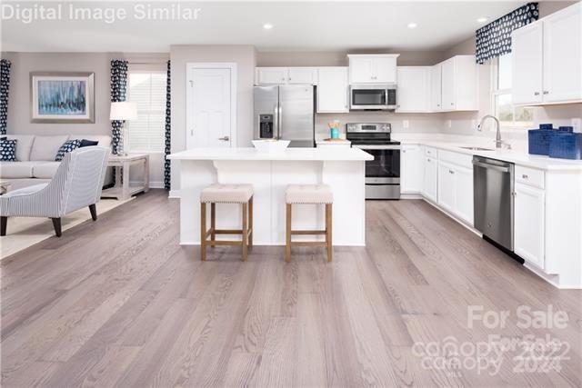 kitchen with a kitchen island, white cabinetry, appliances with stainless steel finishes, and sink