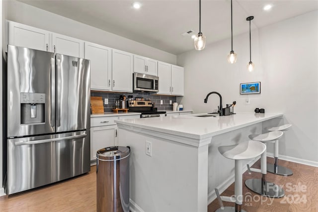 kitchen featuring pendant lighting, sink, tasteful backsplash, white cabinetry, and stainless steel appliances