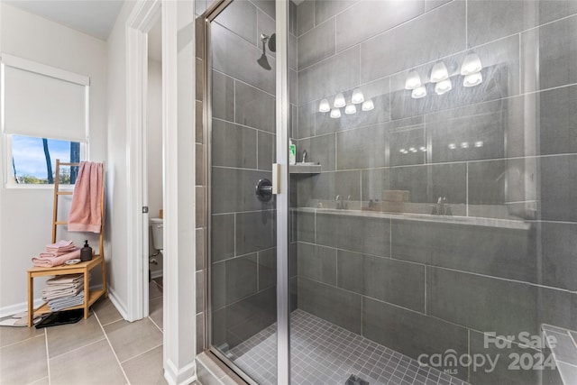 bathroom with tile patterned flooring, an enclosed shower, and toilet