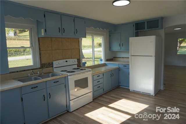 kitchen featuring light wood-type flooring, white appliances, sink, and tasteful backsplash