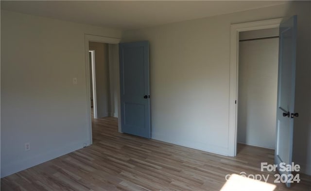 unfurnished bedroom with light wood-type flooring and a closet