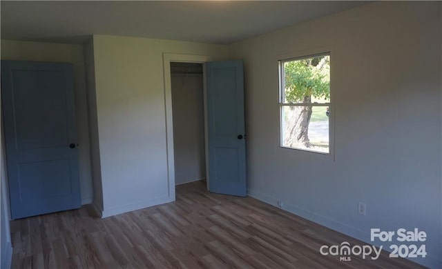 unfurnished bedroom featuring a closet and hardwood / wood-style floors