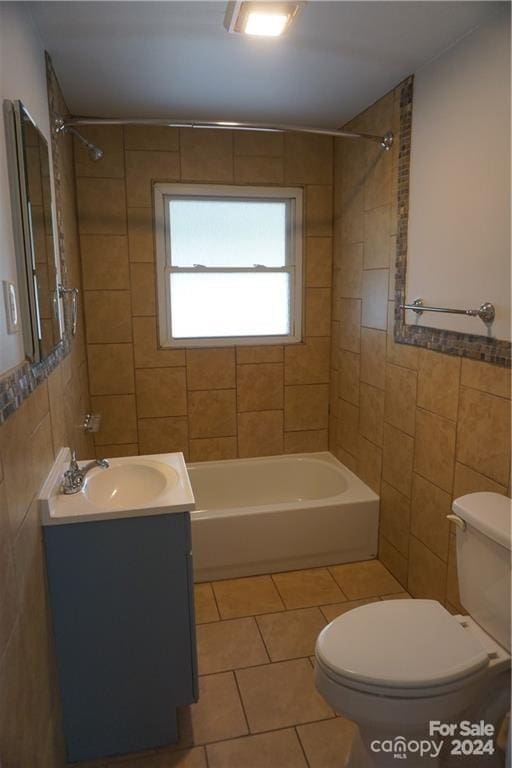 full bathroom with tile patterned flooring, toilet, vanity, tile walls, and tiled shower / bath