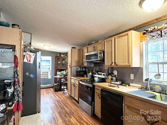 kitchen featuring a textured ceiling, stainless steel appliances, a wealth of natural light, and dark wood-type flooring