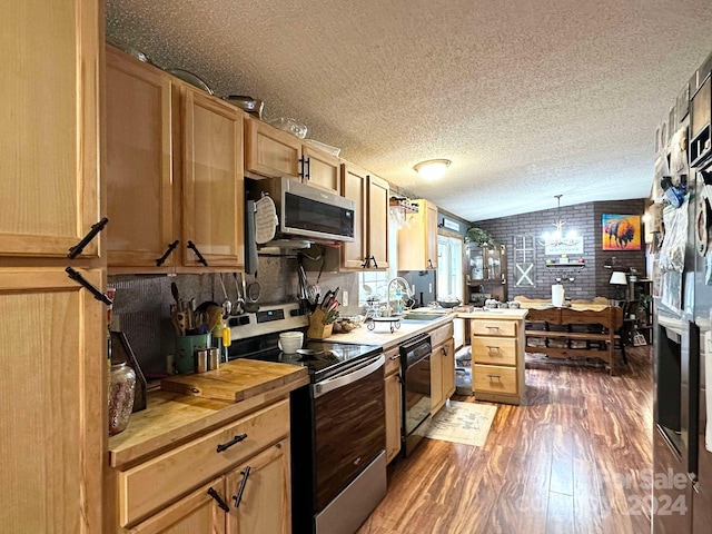 kitchen featuring dark hardwood / wood-style flooring, brick wall, pendant lighting, a textured ceiling, and appliances with stainless steel finishes