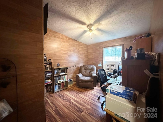 home office featuring hardwood / wood-style floors, a textured ceiling, wooden walls, and lofted ceiling