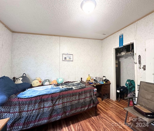 bedroom with crown molding, a textured ceiling, and hardwood / wood-style flooring