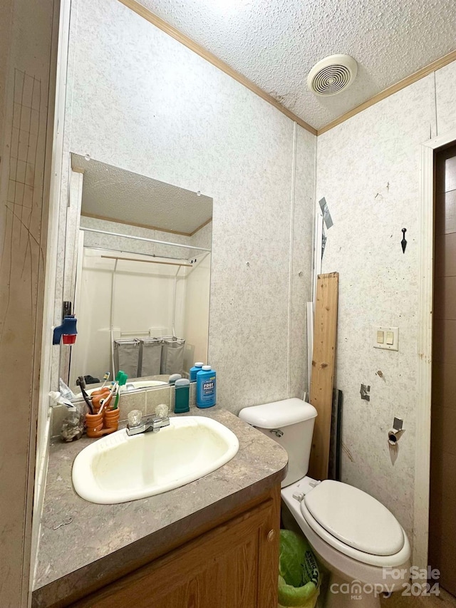 bathroom featuring vanity, toilet, ornamental molding, and a textured ceiling