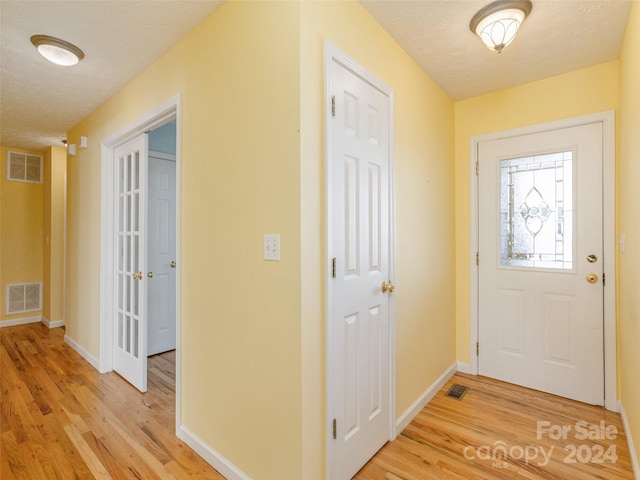 foyer entrance featuring a textured ceiling and light hardwood / wood-style flooring