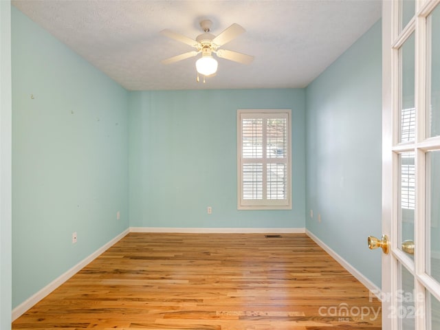 spare room featuring ceiling fan, light hardwood / wood-style floors, and a textured ceiling