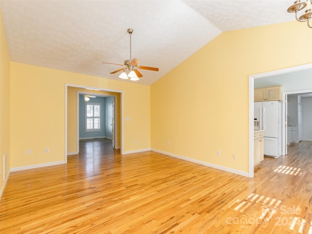 empty room with ceiling fan, light wood-type flooring, a textured ceiling, and vaulted ceiling