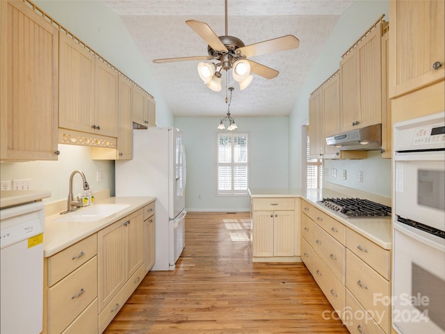 kitchen with white appliances, lofted ceiling, sink, light hardwood / wood-style flooring, and a textured ceiling