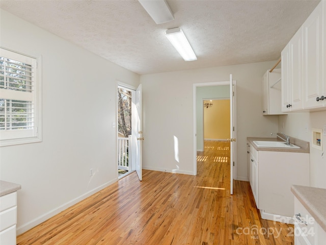 laundry area with cabinets, sink, hookup for a washing machine, and light hardwood / wood-style flooring