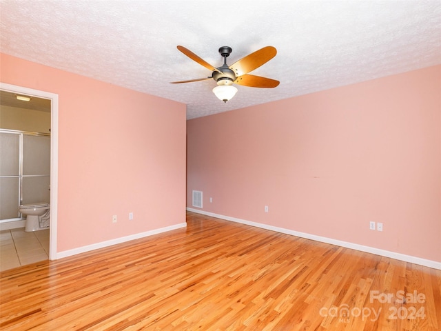 unfurnished room with ceiling fan, light hardwood / wood-style flooring, and a textured ceiling