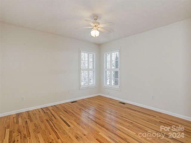 unfurnished room with ceiling fan, light hardwood / wood-style flooring, and a textured ceiling