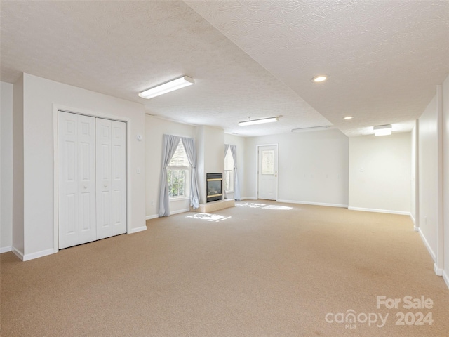 basement featuring light carpet and a textured ceiling