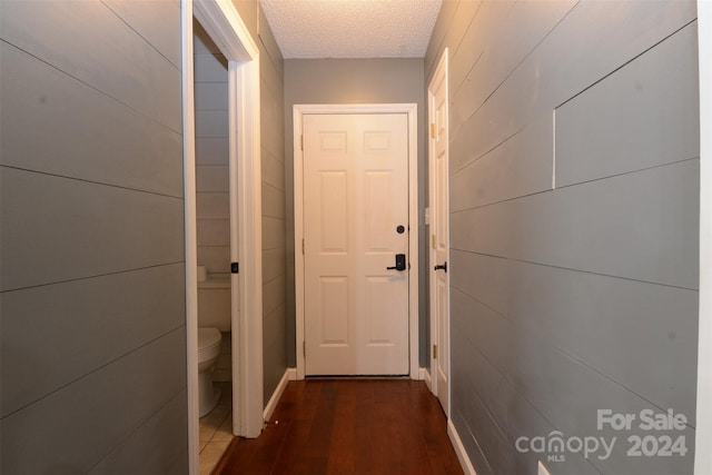 corridor with dark hardwood / wood-style floors and a textured ceiling