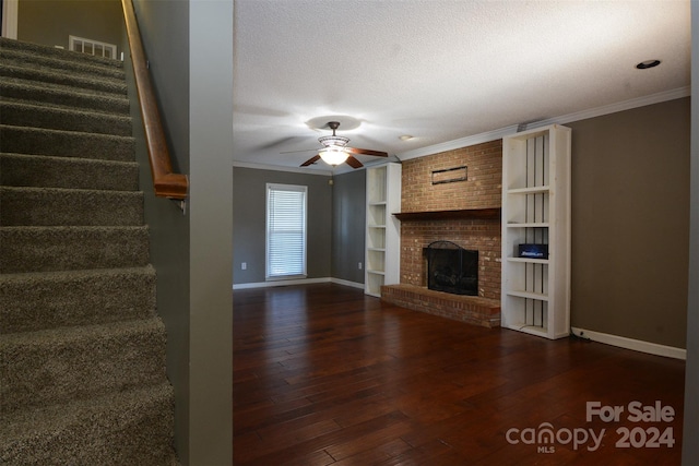 unfurnished living room featuring crown molding, dark hardwood / wood-style flooring, a textured ceiling, and a brick fireplace