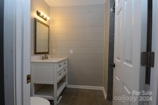 bathroom with tile patterned floors, vanity, and wood walls