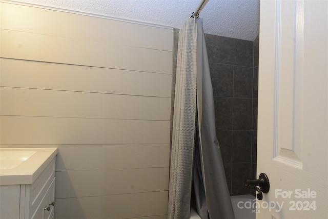 bathroom featuring vanity, shower / bath combination with curtain, and a textured ceiling