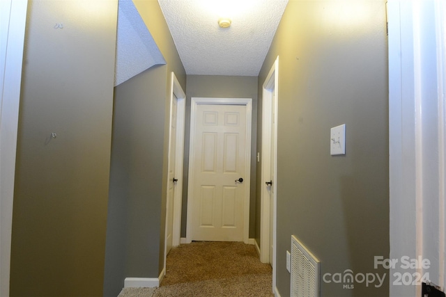 hallway featuring light carpet and a textured ceiling