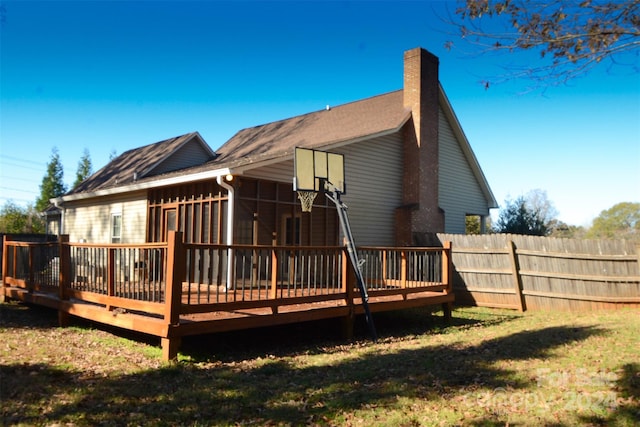 back of house with a sunroom, a wooden deck, and a lawn