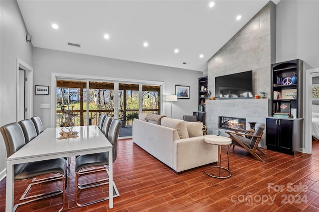 living room with a fireplace, hardwood / wood-style floors, and high vaulted ceiling