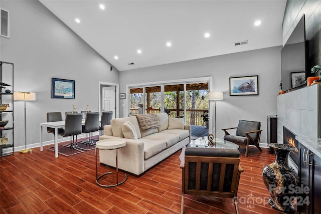 living room featuring a fireplace, high vaulted ceiling, and hardwood / wood-style flooring