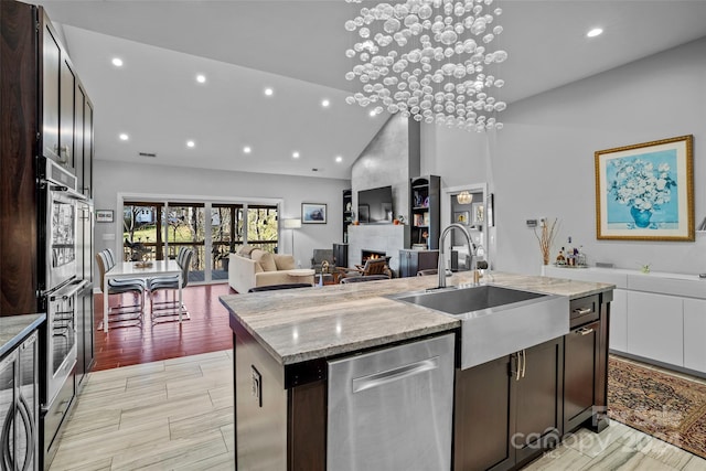 kitchen featuring sink, light hardwood / wood-style floors, an island with sink, a large fireplace, and stainless steel appliances