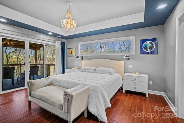 bedroom with a chandelier, dark hardwood / wood-style flooring, access to outside, and a raised ceiling