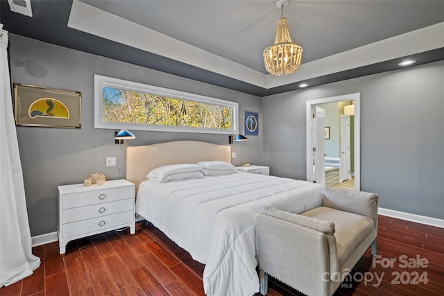 bedroom with dark hardwood / wood-style flooring, connected bathroom, and a chandelier