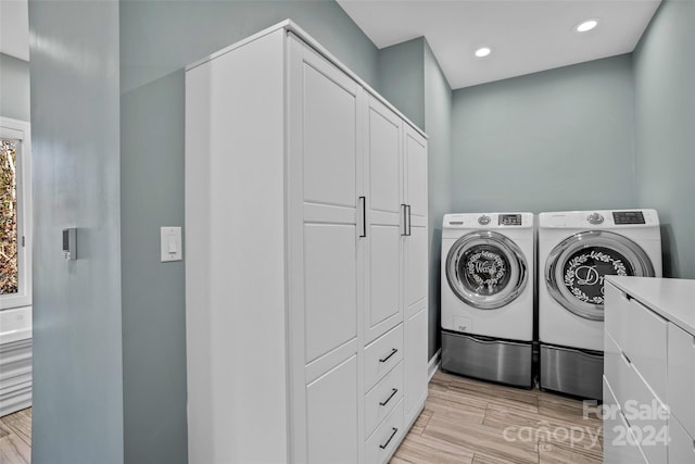 clothes washing area featuring light hardwood / wood-style flooring, cabinets, and independent washer and dryer