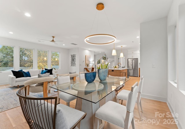 dining space featuring ceiling fan, sink, and light hardwood / wood-style flooring