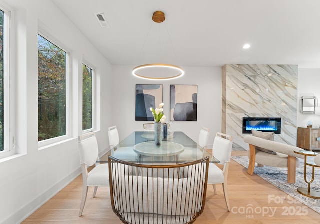 dining room with light hardwood / wood-style floors and a high end fireplace