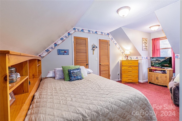 carpeted bedroom with two closets and lofted ceiling