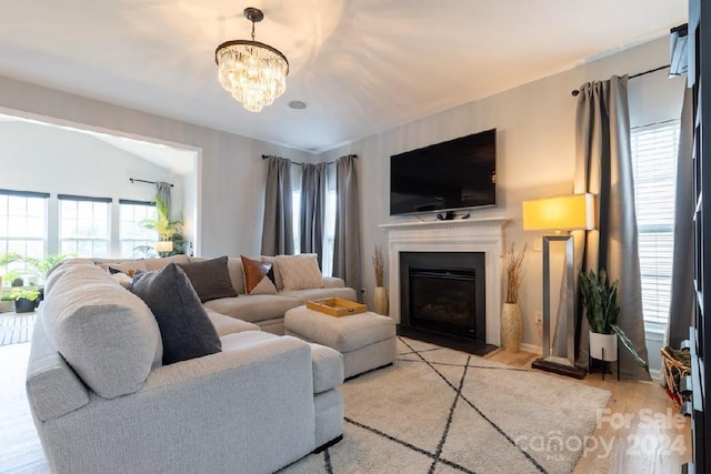 living room with light wood-type flooring, a wealth of natural light, and a chandelier