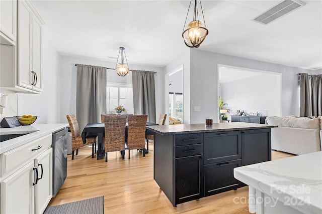 kitchen featuring hanging light fixtures, a kitchen island, stainless steel dishwasher, white cabinets, and light wood-type flooring