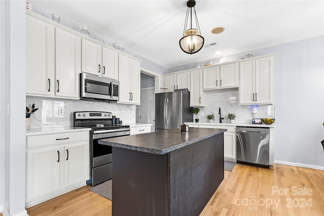 kitchen featuring appliances with stainless steel finishes, a kitchen island, white cabinetry, and pendant lighting