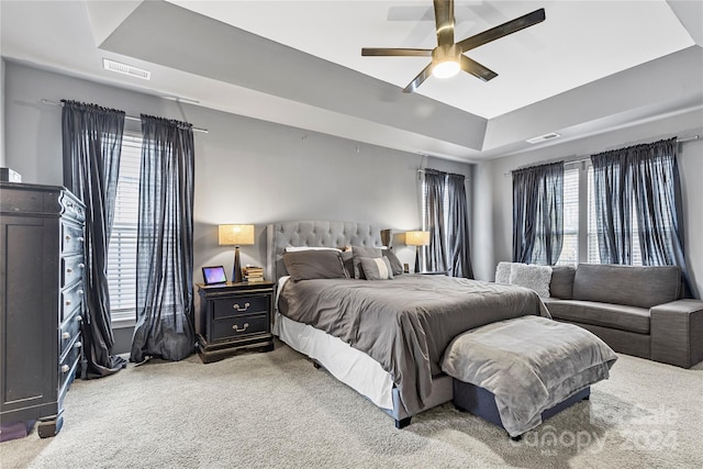 bedroom with carpet flooring, a raised ceiling, and ceiling fan