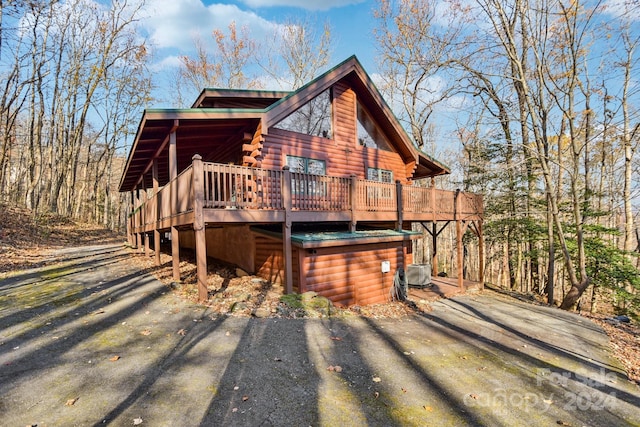 log-style house featuring cooling unit and a wooden deck