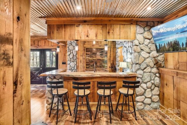 bar featuring wooden walls, hardwood / wood-style floors, wood ceiling, and french doors