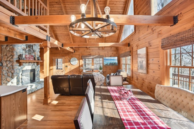 dining space with beamed ceiling, a healthy amount of sunlight, and wooden walls