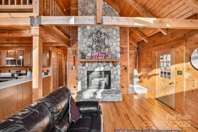 living room with wood walls, wood ceiling, lofted ceiling with beams, hardwood / wood-style flooring, and a fireplace