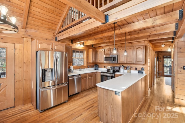 kitchen with appliances with stainless steel finishes, wooden walls, sink, hanging light fixtures, and wood ceiling