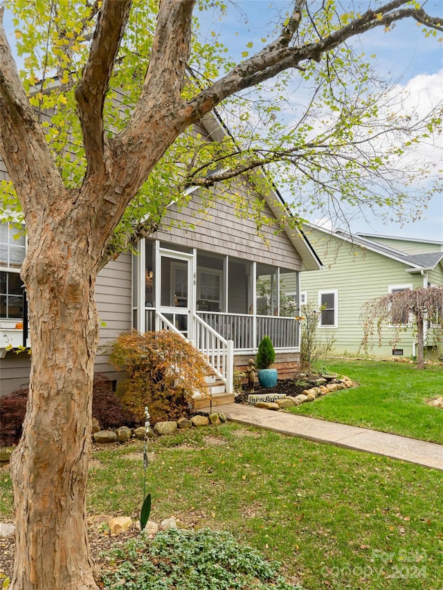 view of front of home featuring a sunroom and a front lawn