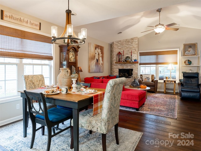 dining room featuring dark hardwood / wood-style floors, a fireplace, ceiling fan with notable chandelier, and vaulted ceiling