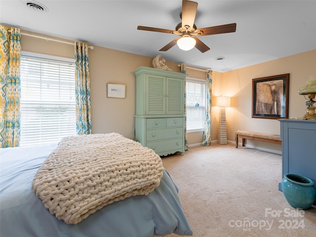 bedroom featuring light colored carpet, multiple windows, and ceiling fan