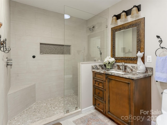 bathroom with a tile shower, vanity, and toilet