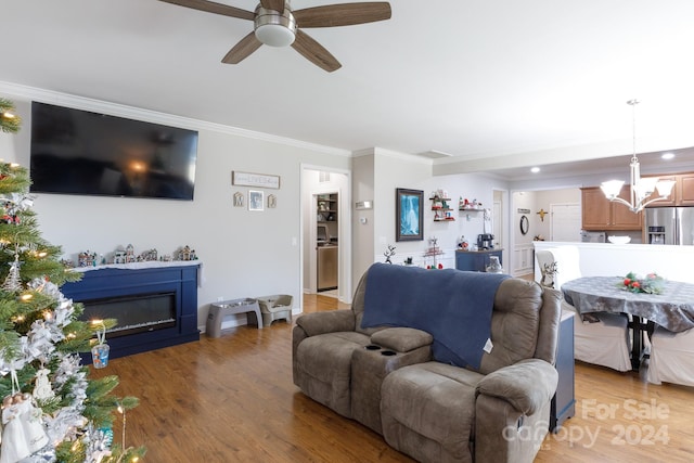 living room featuring ceiling fan with notable chandelier, light wood-type flooring, and ornamental molding